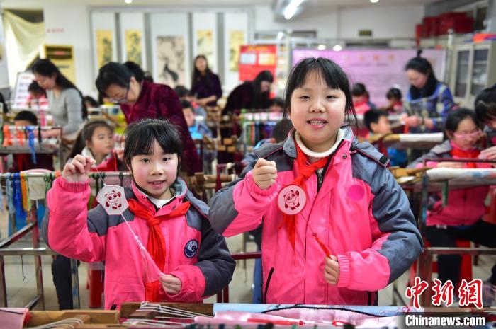 圖為小學(xué)生展示繡制好的2022年北京冬奧會(huì)吉祥物“冰墩墩”形象。　喻云亮 攝