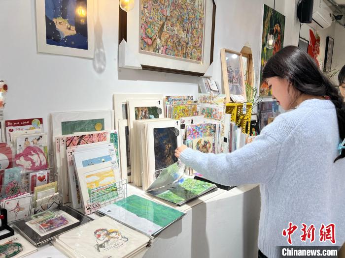 圖為藝術(shù)品商店內(nèi)，顧客挑選插畫作品。　鐘旖 攝