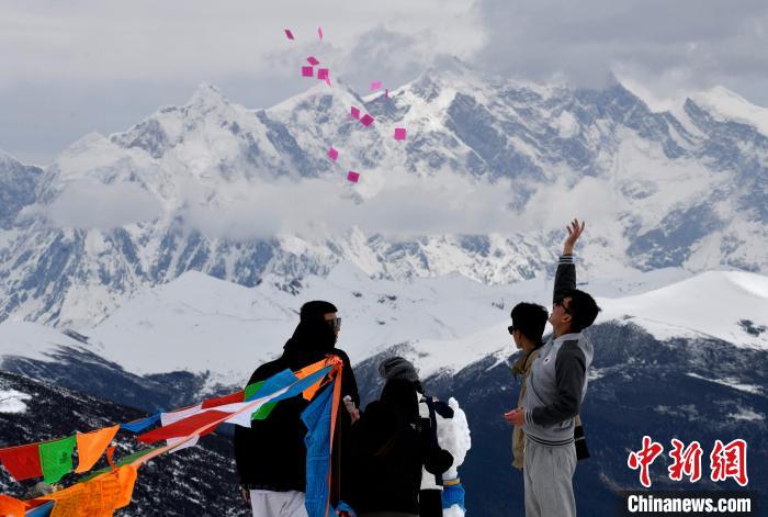 圖為5月14日，游客在西藏林芝色季拉山觀景臺拋灑“隆達”(風馬旗，藏族民眾的一種祈福方式)?！±盍?攝